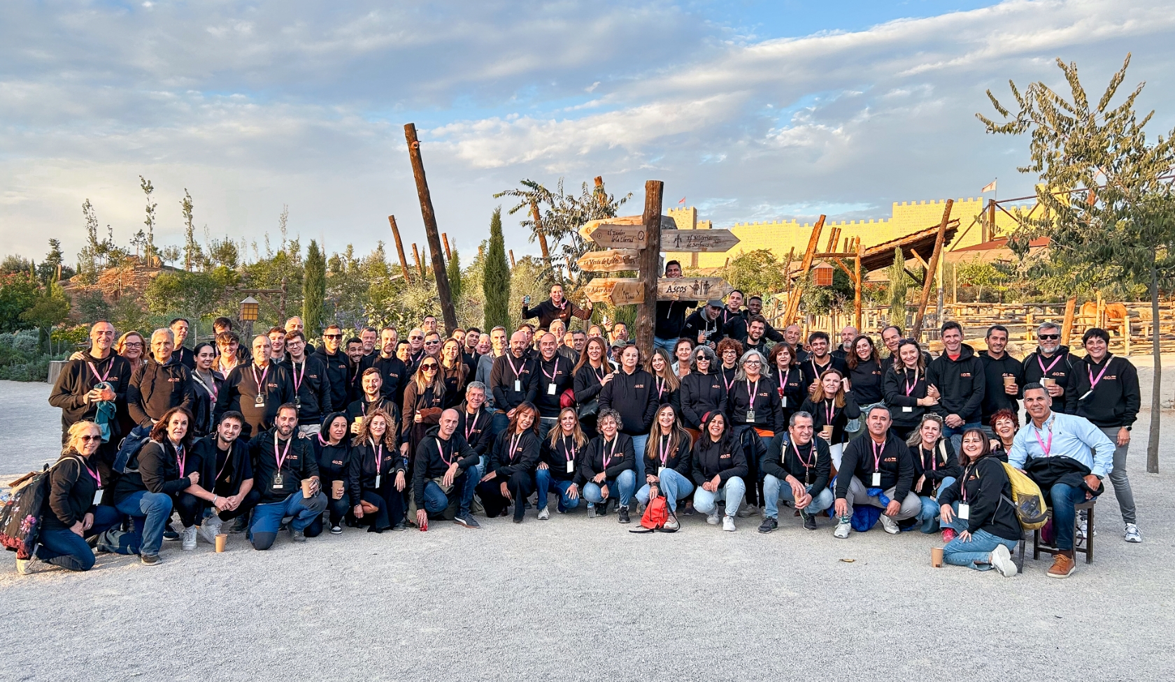 Large STIHL employee group in park before pavilion, all wearing company clothing and badges, orange STIHL sign in front